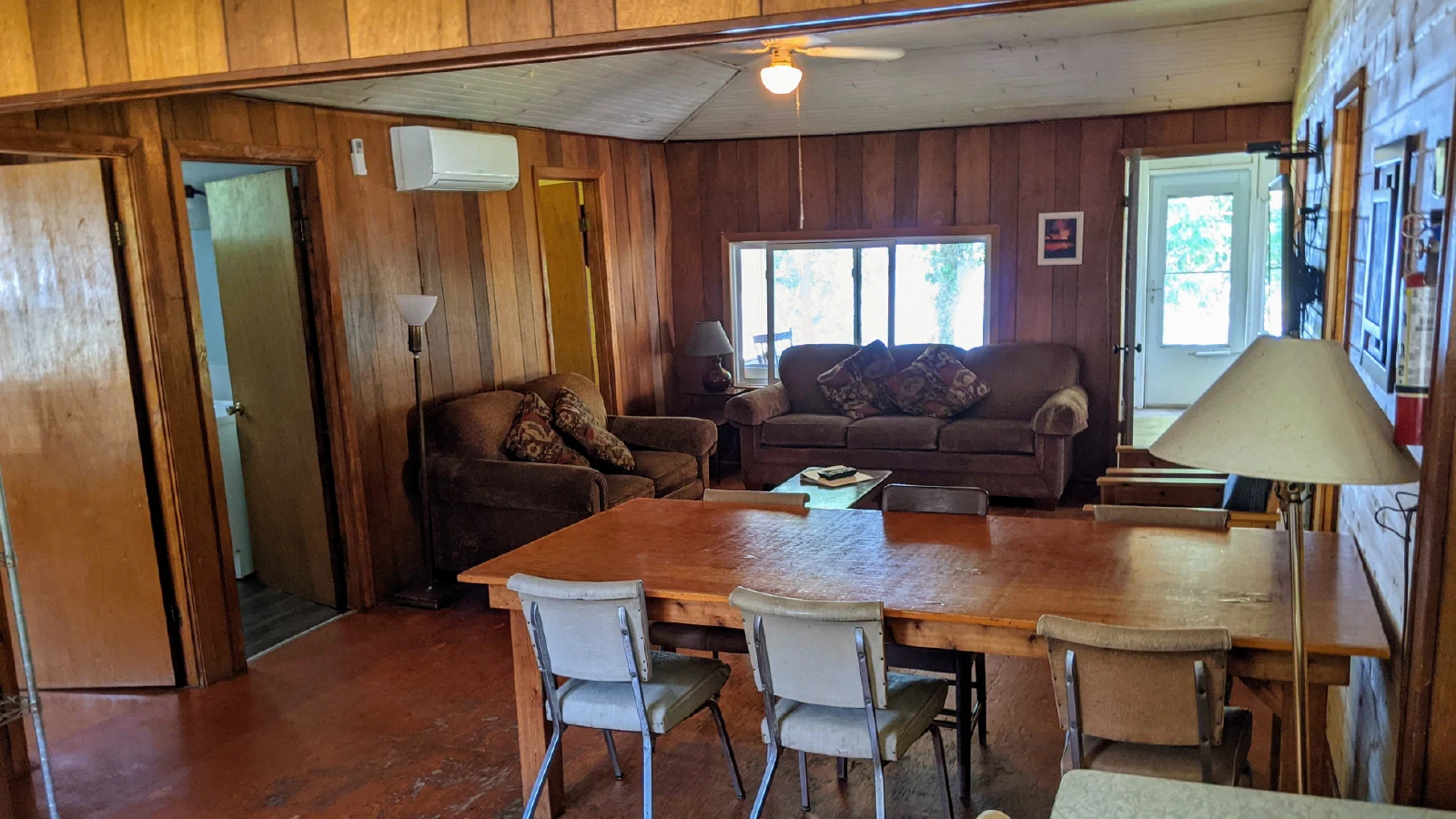 Pigeon Lake Resort Cottage three open-concept living and dining area with table, chairs, sofas, and window view.